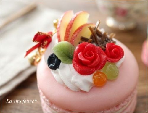 ピンクのマカロンに赤いバラとスライスりんごや刻んだチョコをのせたフェイクスイーツ
